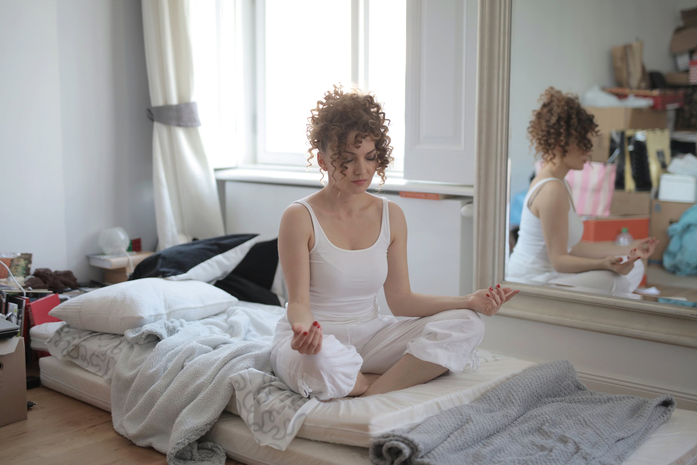 Calm woman in lotus pose meditating after awakening at home