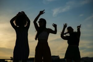 Anonymous girlfriends dancing against sunset sky